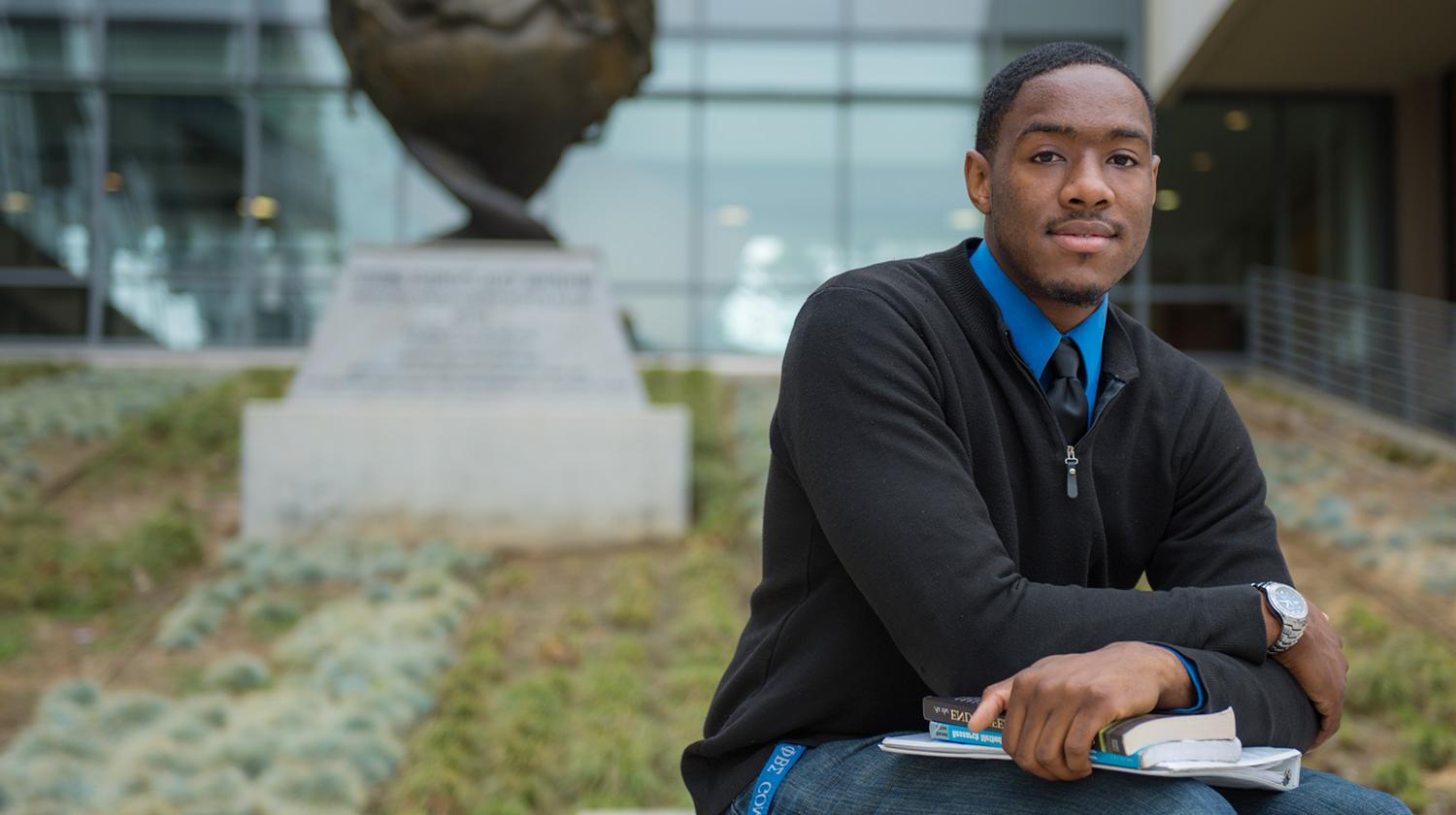 alumni scholarship recipient Aaron Street in front of the sculpture